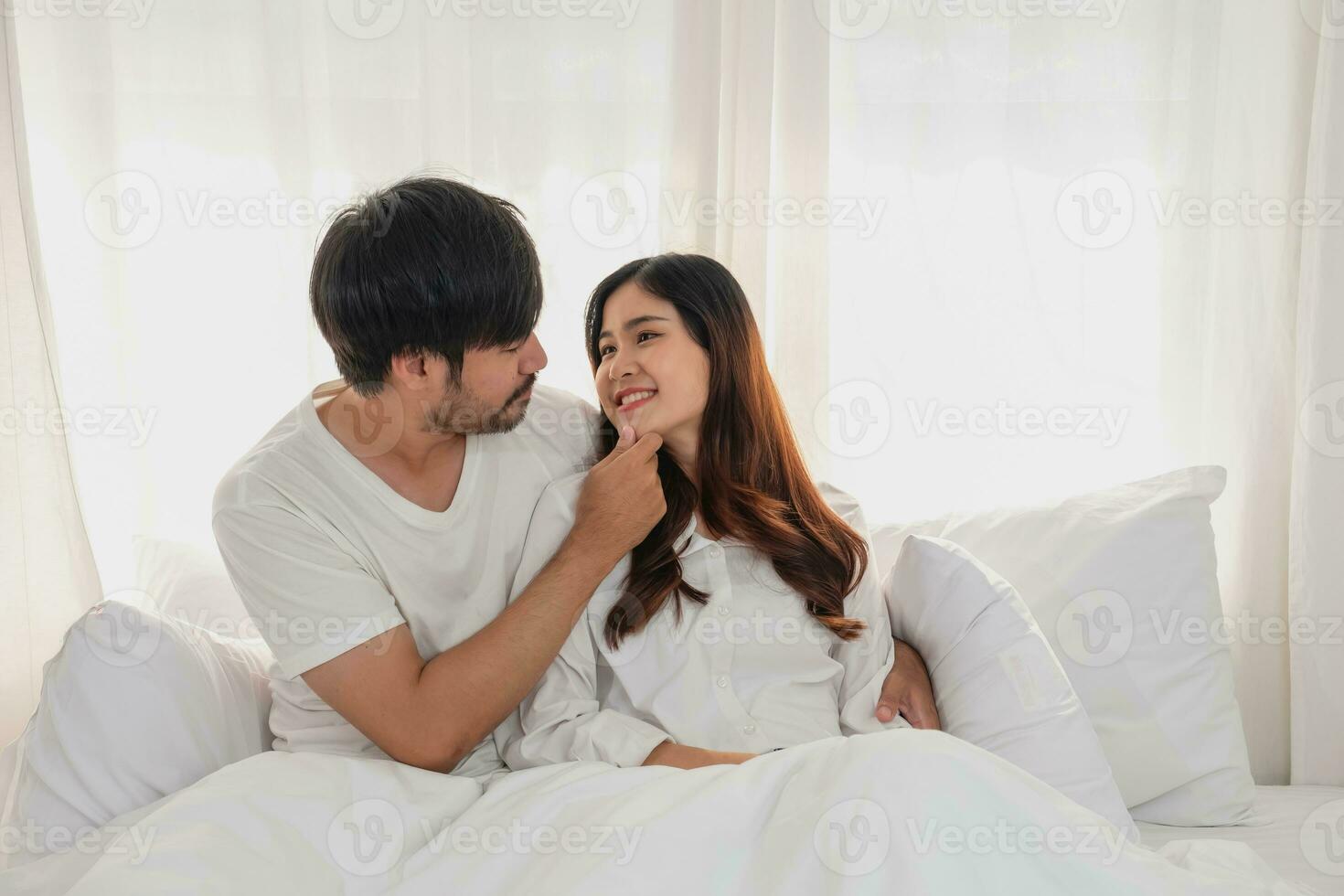 contento joven asiático Pareja abrazando, broma, jugando alegremente en cama a hogar, romántico hora a mejorar familia vinculación familia concepto. foto