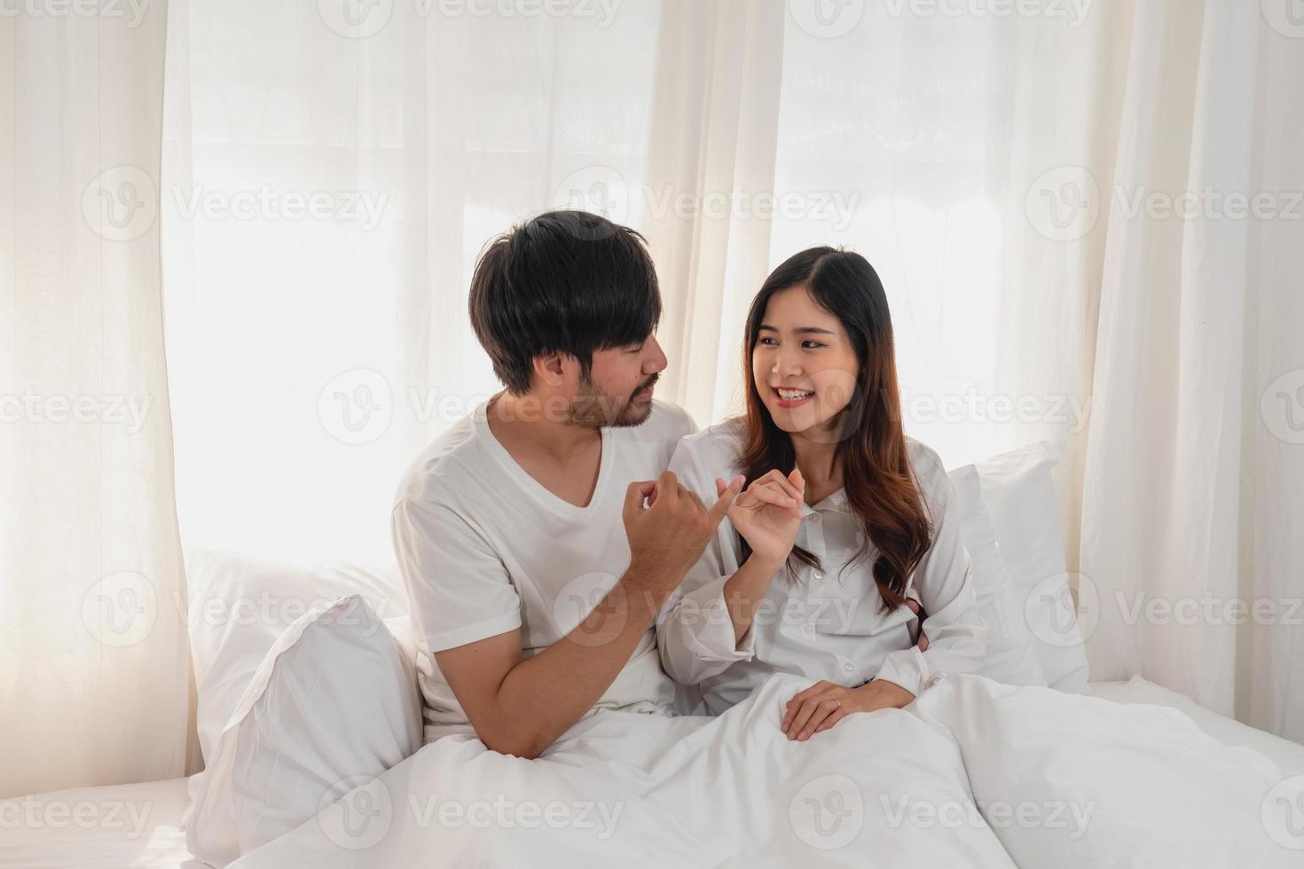 Happy young asian couple embracing, teasing, playing cheerfully in bed at home, romantic time to enhance family bonding. family concept. photo
