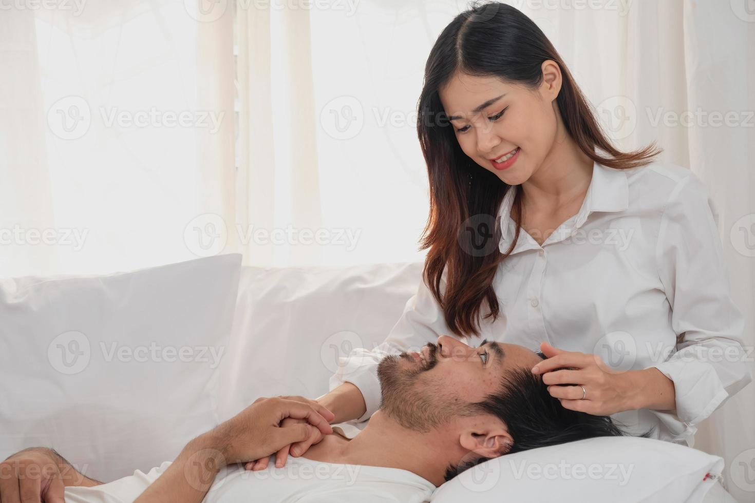 Happy young asian couple embracing, teasing, playing cheerfully in bed at home, romantic time to enhance family bonding. family concept. photo