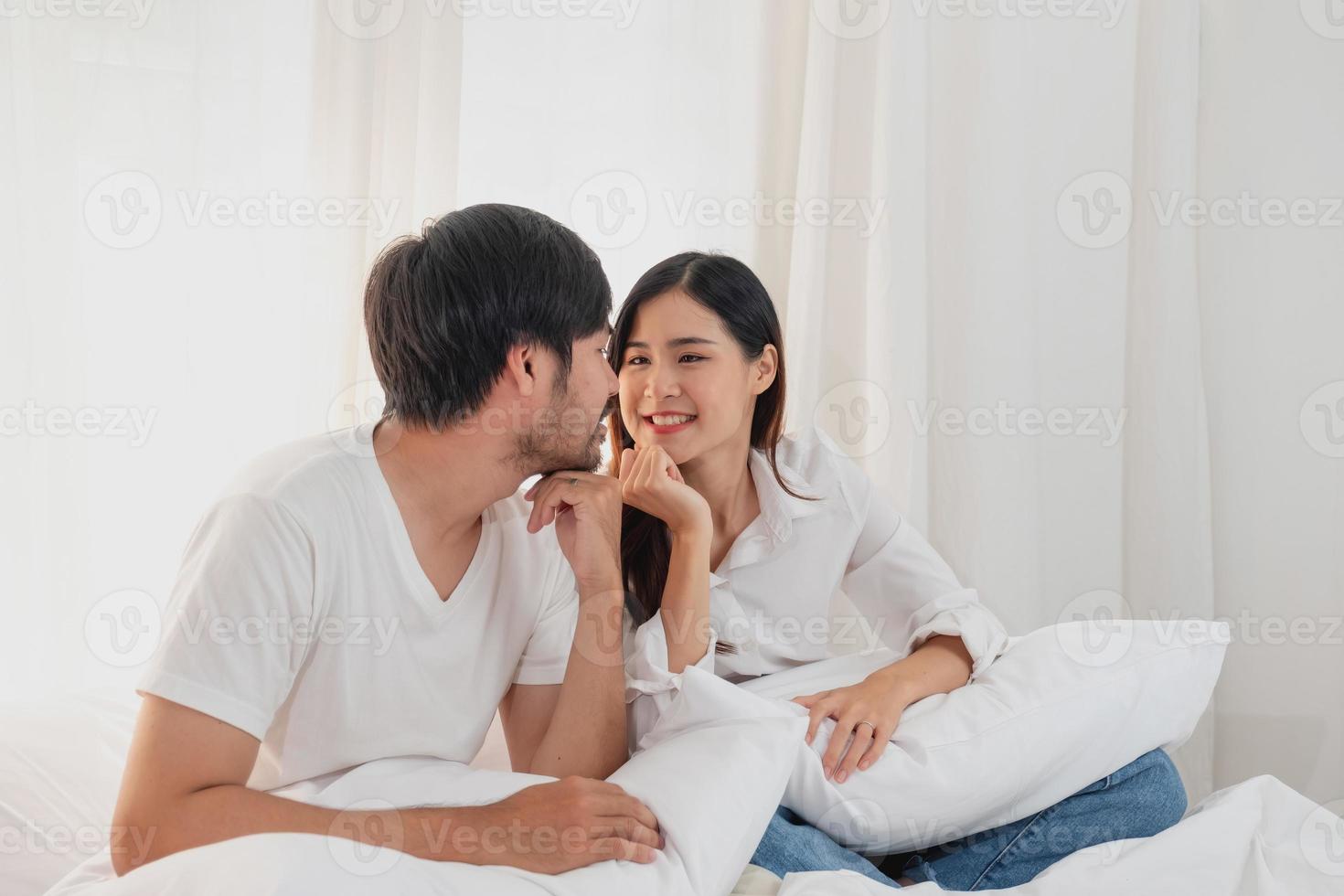 contento joven asiático Pareja abrazando, broma, jugando alegremente en cama a hogar, romántico hora a mejorar familia vinculación familia concepto. foto