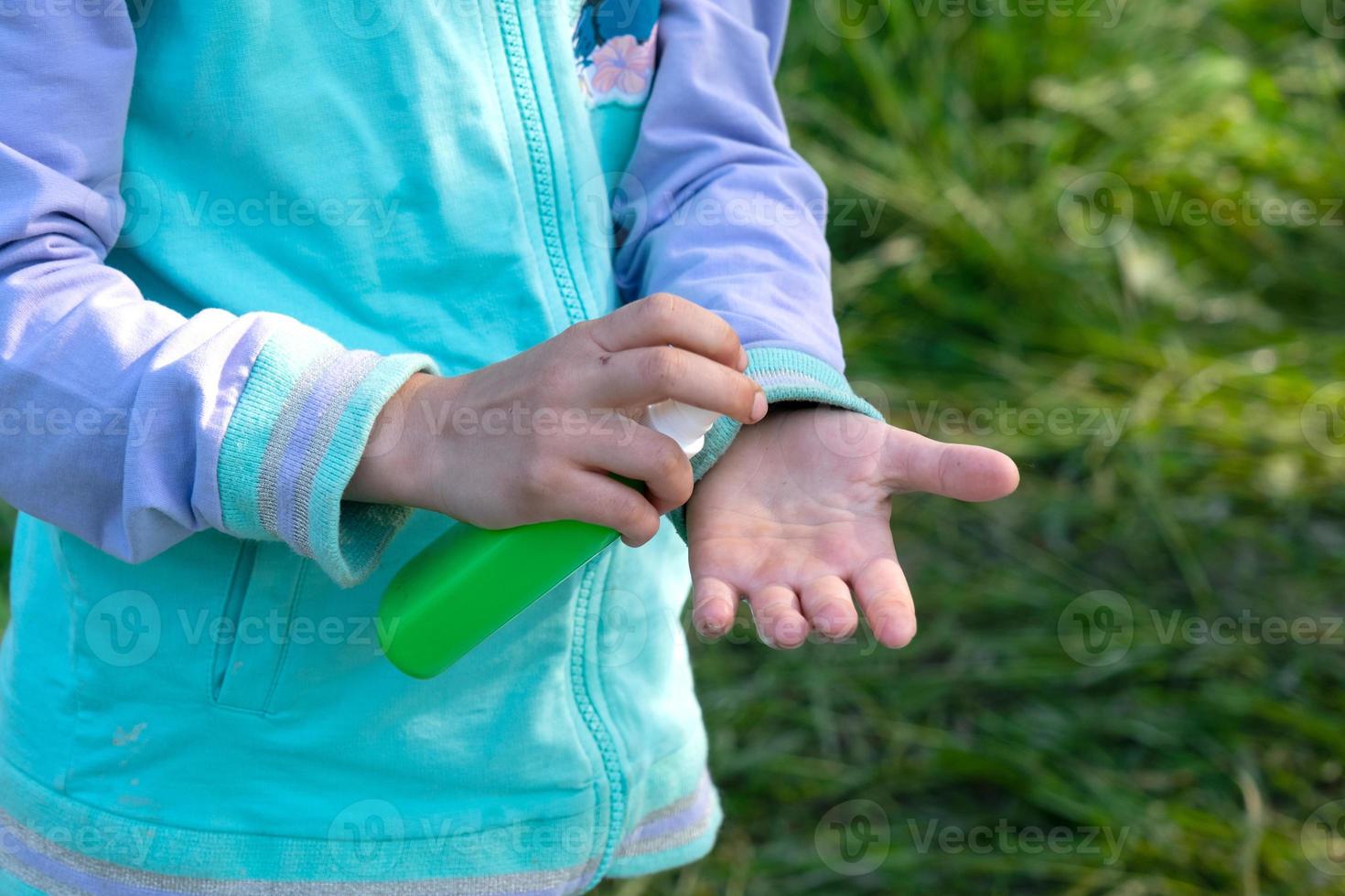 Girl sprays mosquito spray on the skin in nature that bite her hands and feet. Protection from insect bites, repellent safe for children. Outdoor recreation, against allergies. Summer time photo