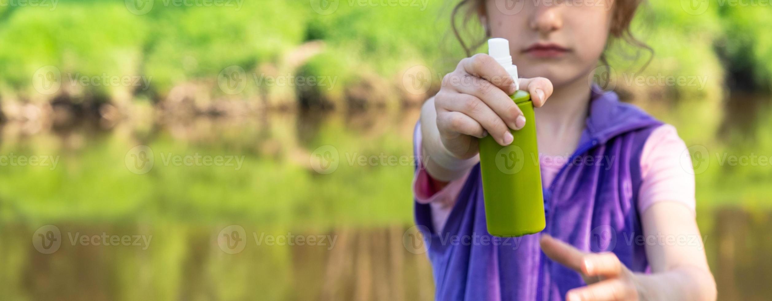 Girl sprays mosquito spray on the skin in nature that bite her hands and feet. Protection from insect bites, repellent safe for children. Outdoor recreation, against allergies. Summer time photo