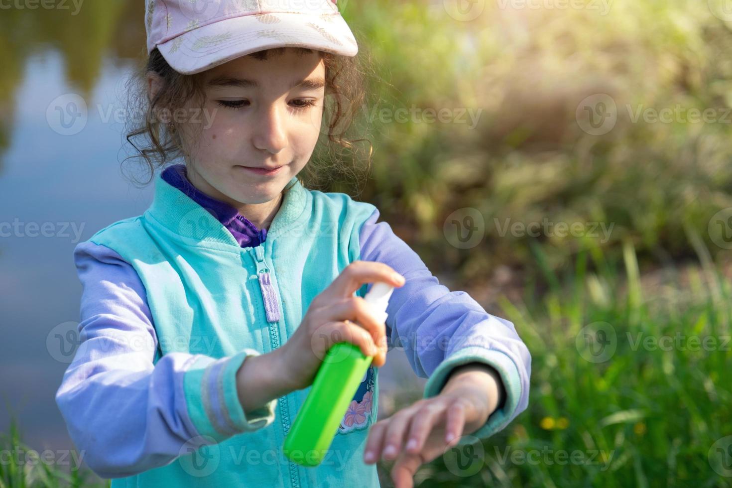 Girl sprays mosquito spray on the skin in nature that bite her hands and feet. Protection from insect bites, repellent safe for children. Outdoor recreation, against allergies. Summer time photo