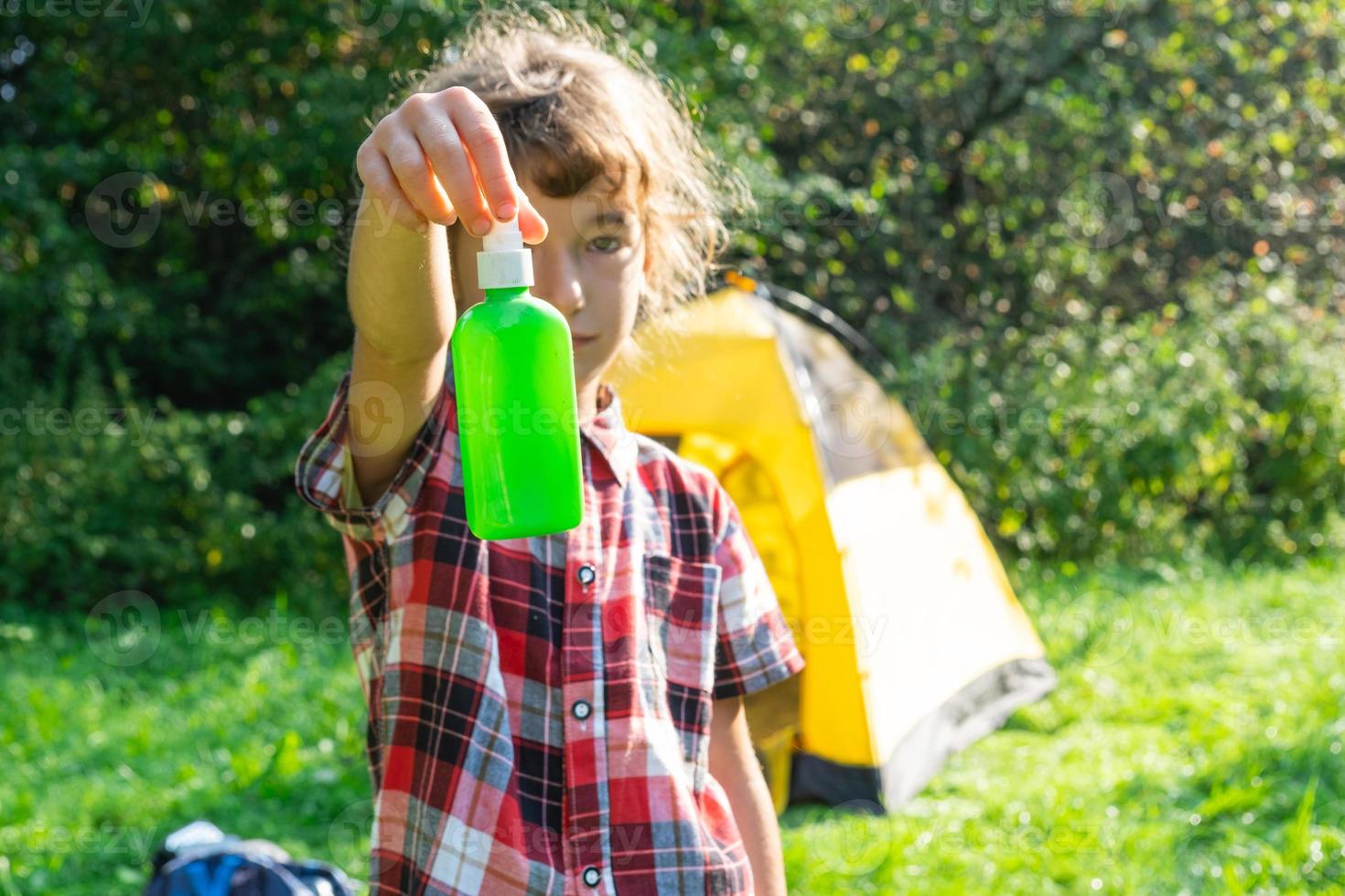 Girl sprays mosquito spray on the skin in nature that bite her hands and feet. Protection from insect bites, repellent safe for children. Outdoor recreation, against allergies. Summer time photo