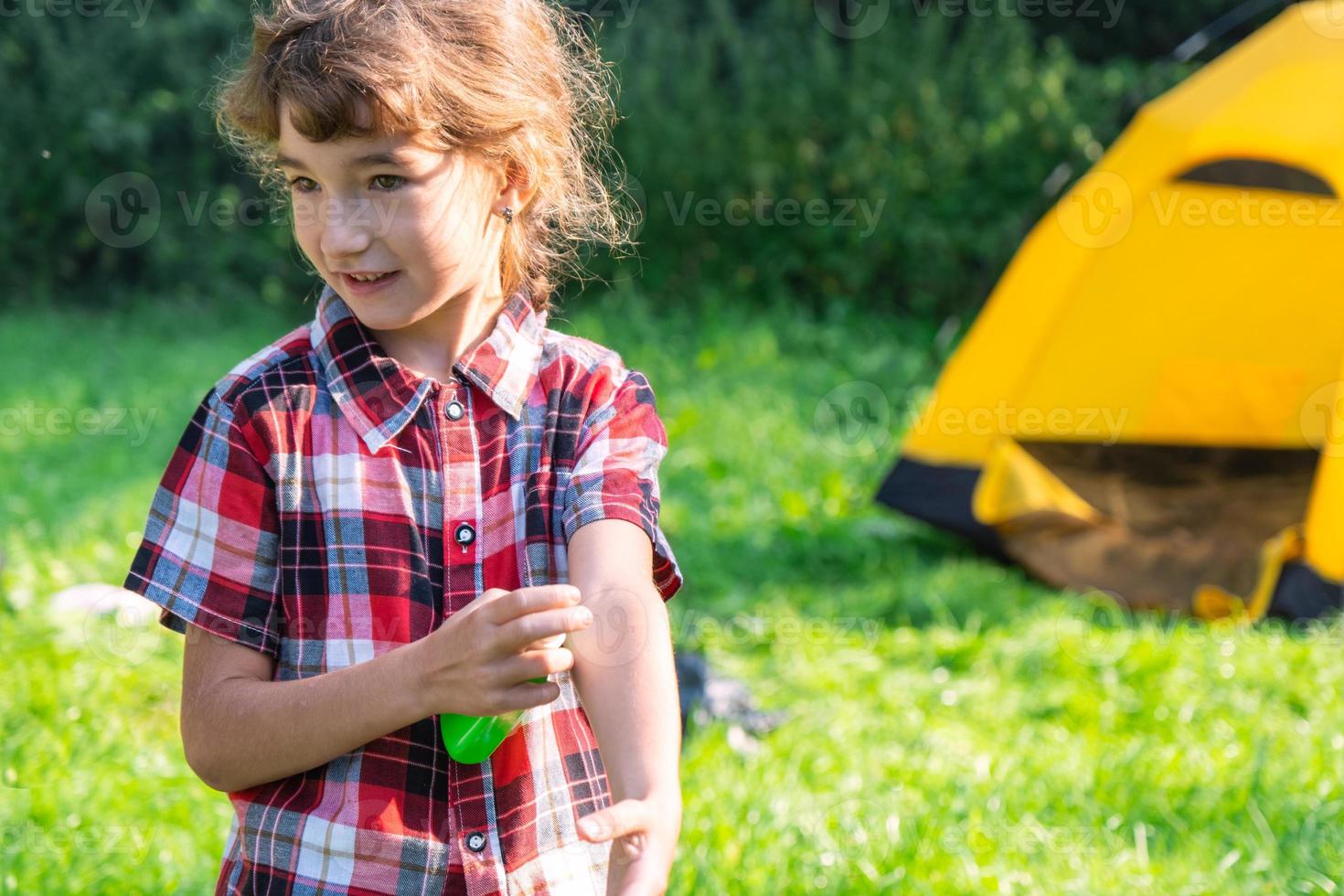 Girl sprays mosquito spray on the skin in nature that bite her hands and feet. Protection from insect bites, repellent safe for children. Outdoor recreation, against allergies. Summer time photo
