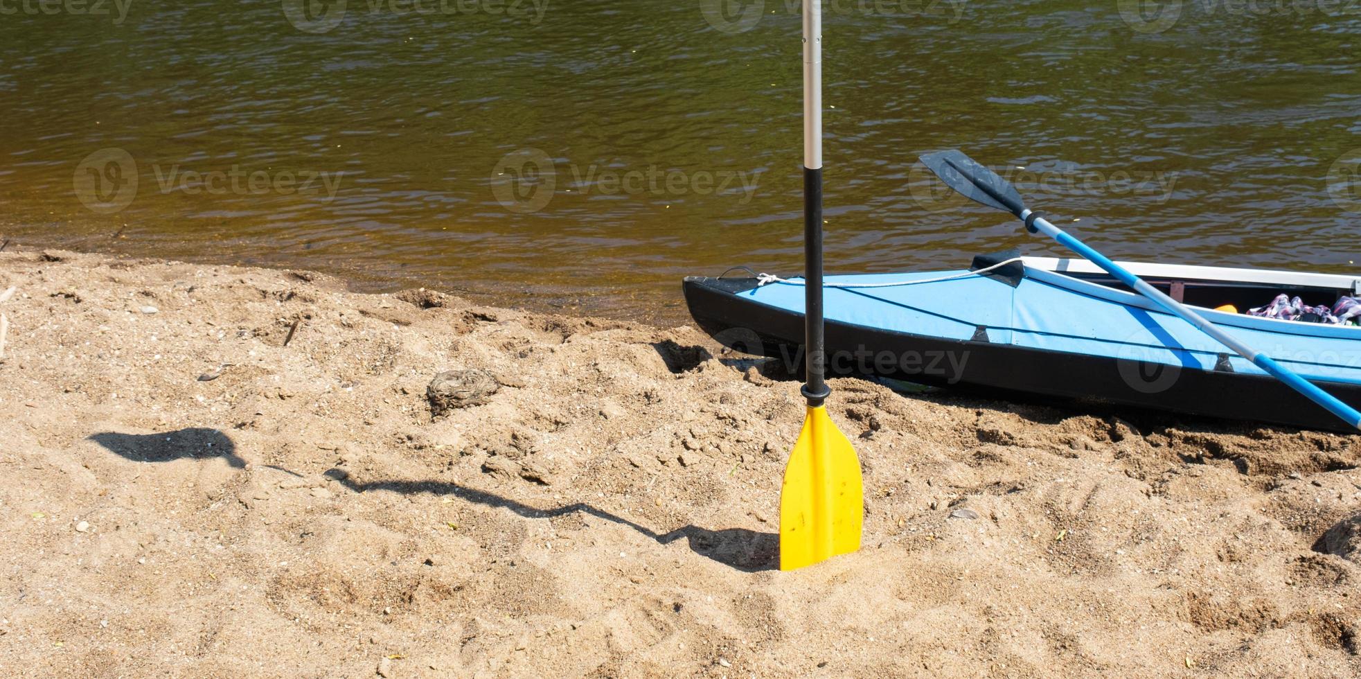 Tourist canoes with paddles stand on the river coast in summer on a water hike. Rafting on inflatable and frame double and triple kayak boats, family trip, extreme adventure in summer photo