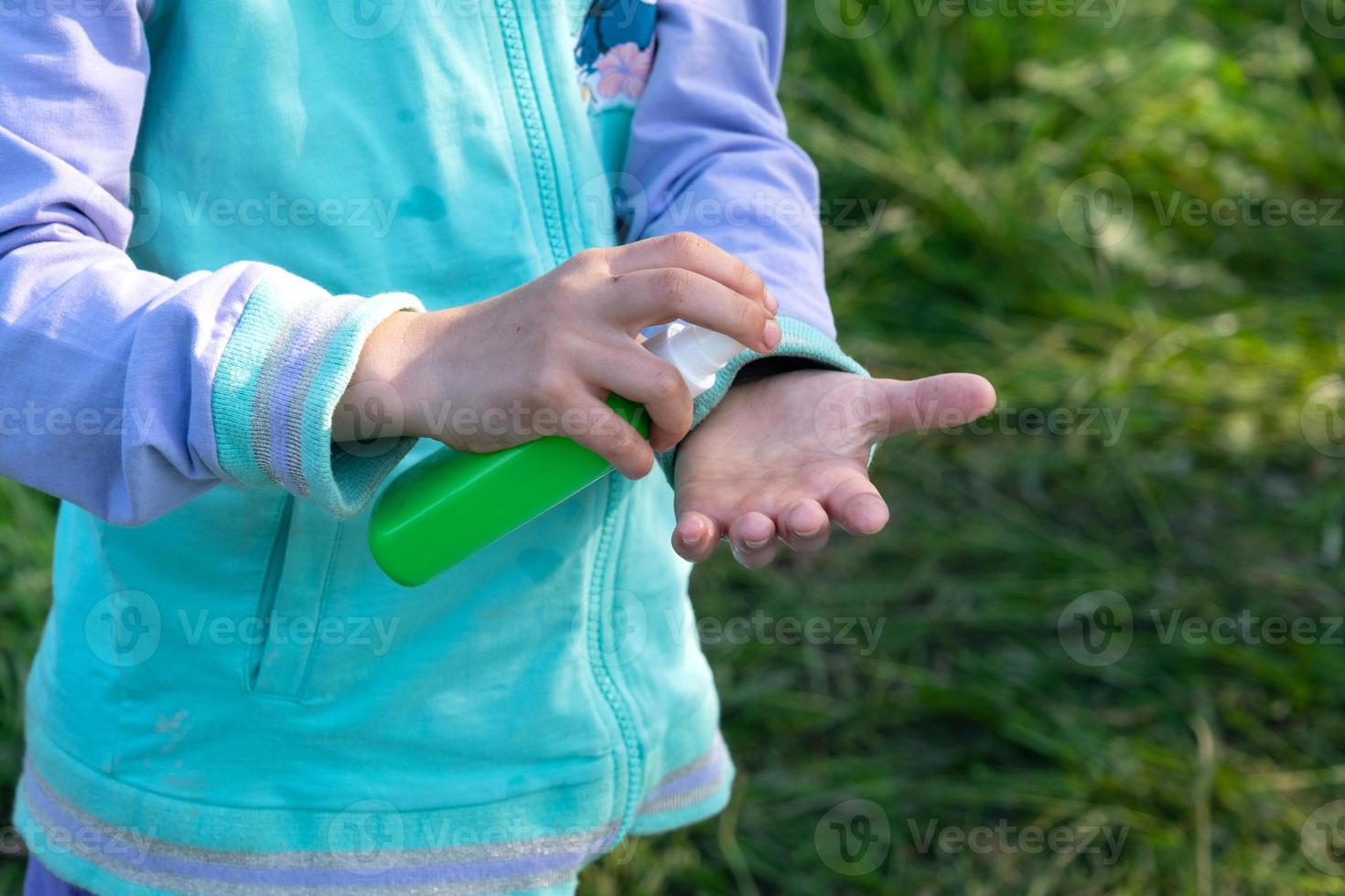 Girl sprays mosquito spray on the skin in nature that bite her hands and feet. Protection from insect bites, repellent safe for children. Outdoor recreation, against allergies. Summer time photo