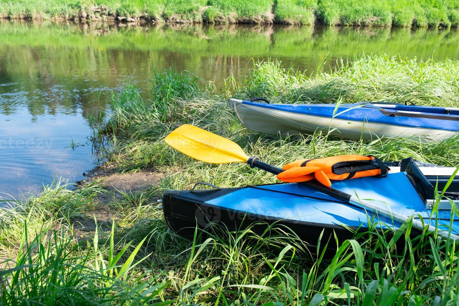 Tourist canoes with paddles stand on the river coast in summer on a water hike. Rafting on inflatable and frame double and triple kayak boats, family trip, extreme adventure in summer photo