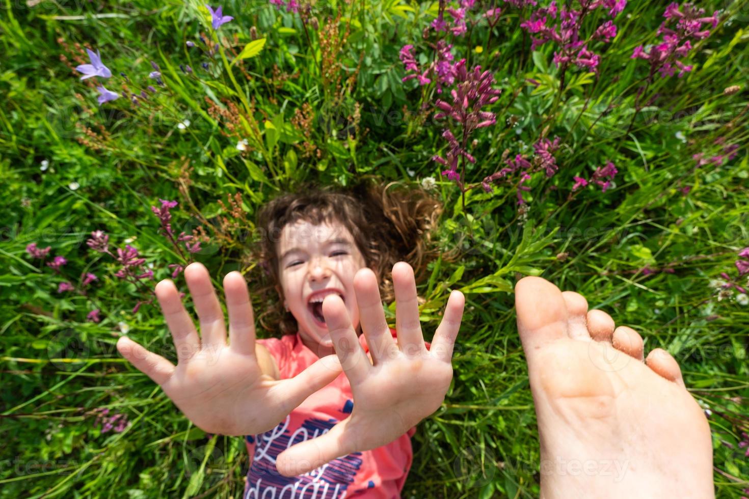 retrato de un niño niña en verano acostado en el césped y flores silvestres con tacones y palmas verano tiempo, libertad foto