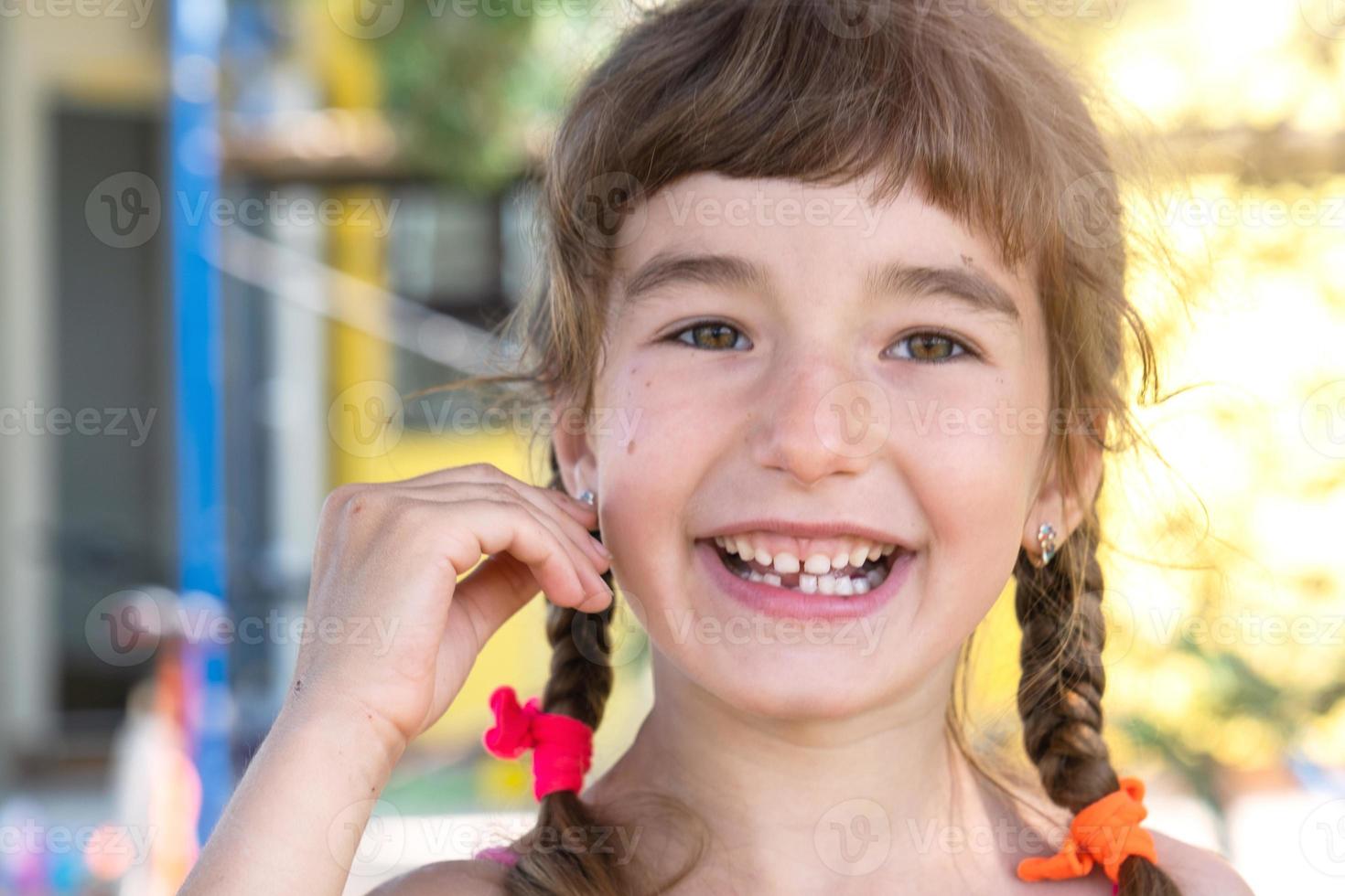 Toothless happy smile of a girl with a fallen lower milk tooth close-up. Changing teeth to molars in childhood photo