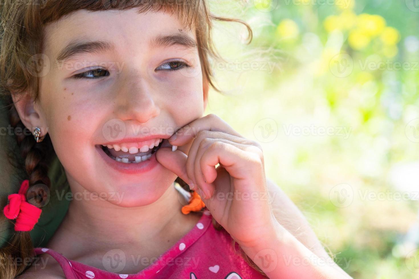 Toothless happy smile of a girl with a fallen lower milk tooth close-up. Changing teeth to molars in childhood photo