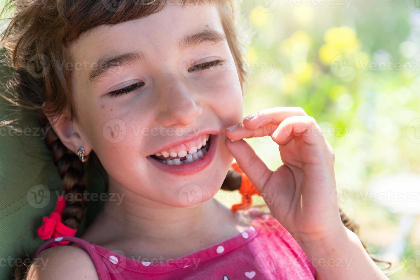 Toothless happy smile of a girl with a fallen lower milk tooth close-up. Changing teeth to molars in childhood photo