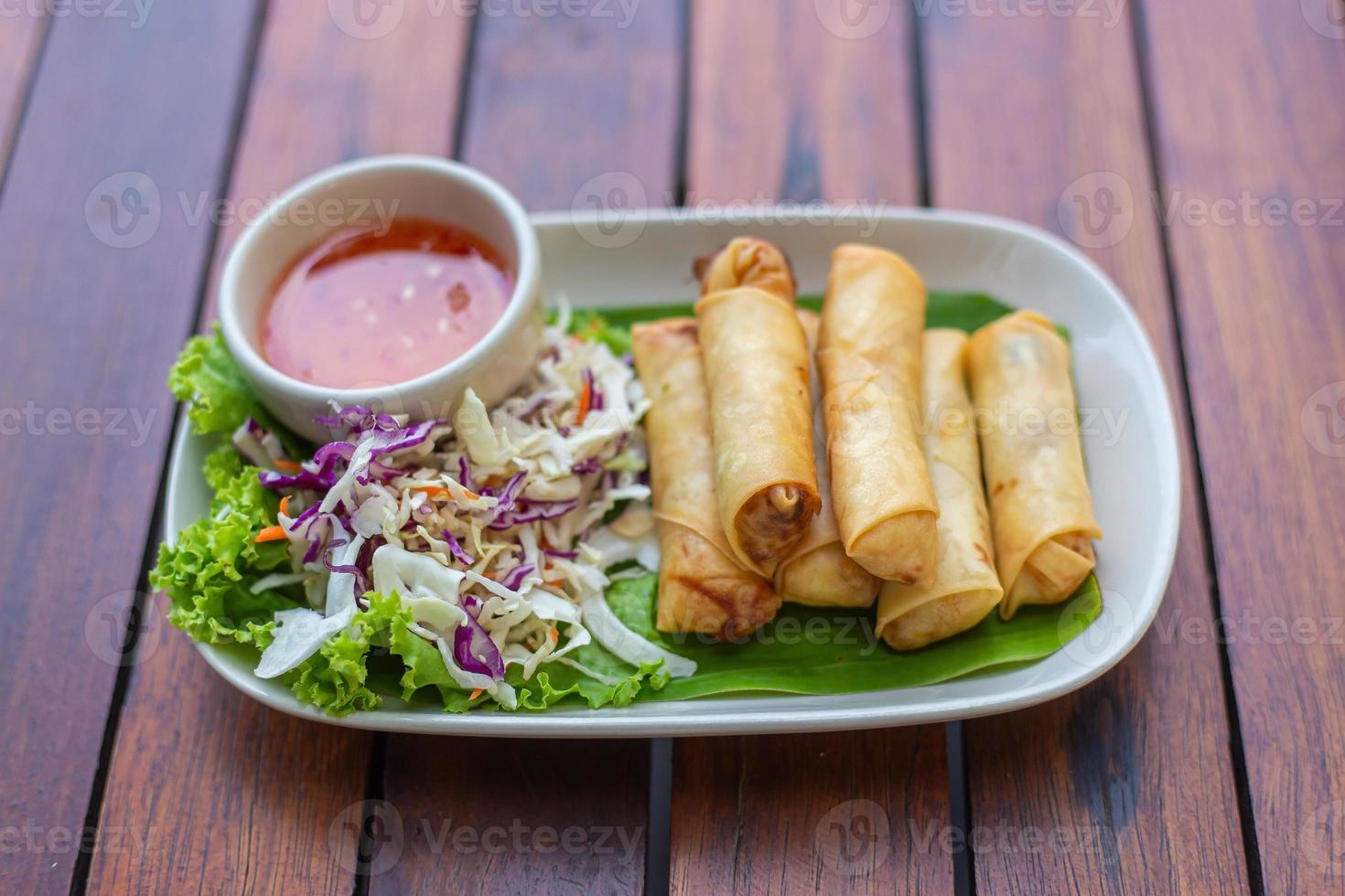 Deep fried spring rolls Por Pieer Tod or Fried spring rolls Thai Spring Roll Served with vegetables and dipping sauce on the wooden table snacks that are popular with Thai and Chinese people. photo