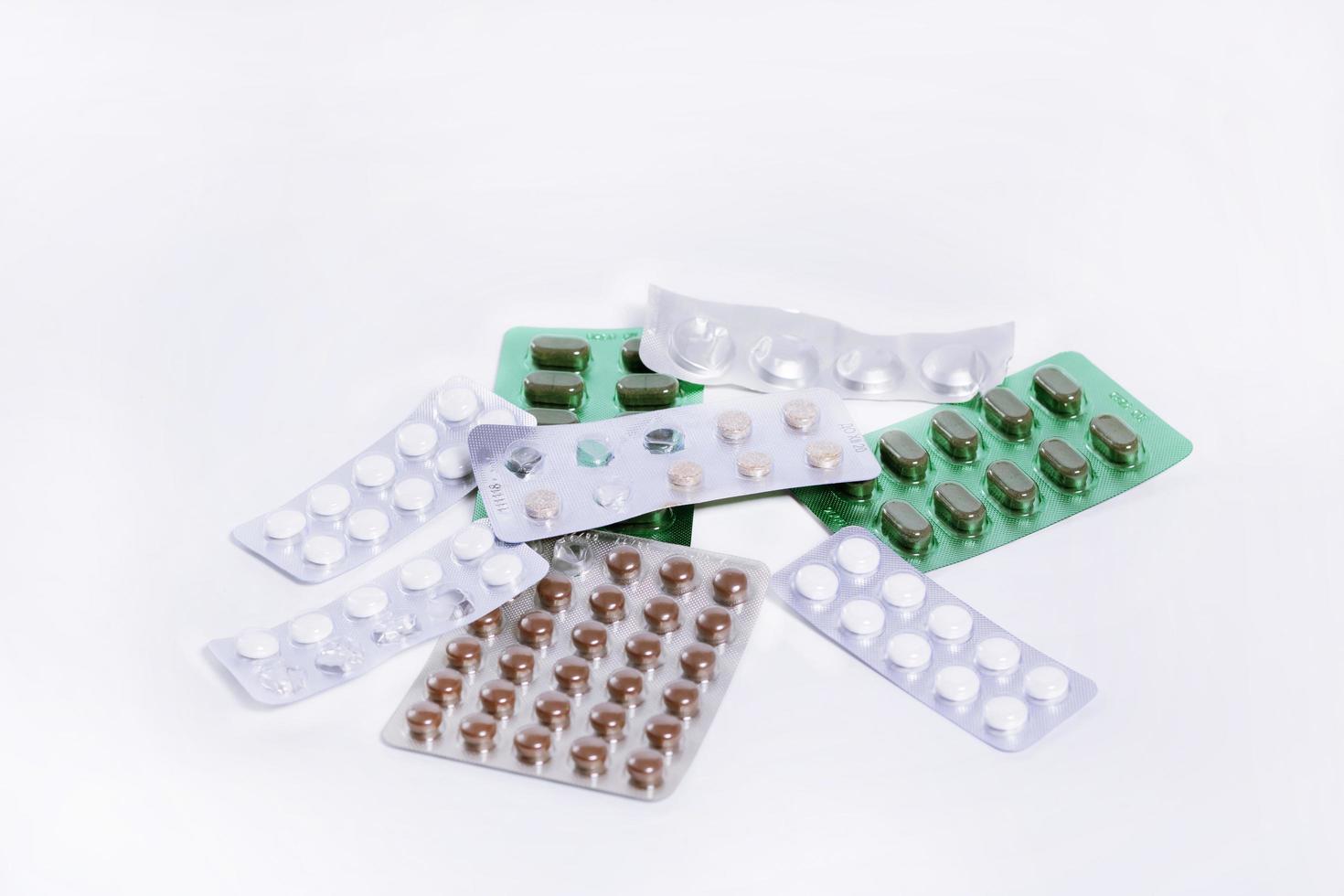 plates with pills from different medical drugs lie in a pile on a white background photo