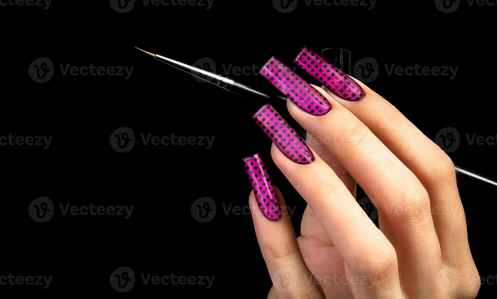 Hand with a beautiful manicure and a brush on a black background. Nail design. Extended nails. photo