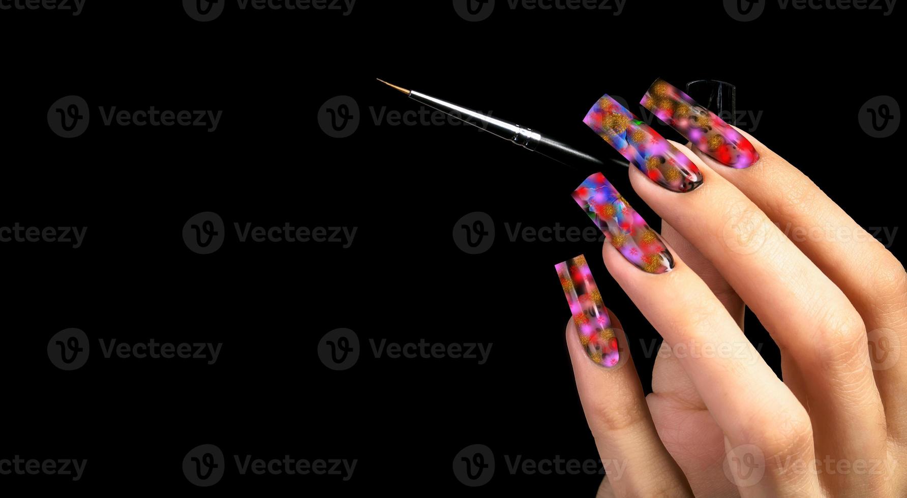 Hand with a beautiful manicure and a brush on a black background. Nail design. Extended nails. photo