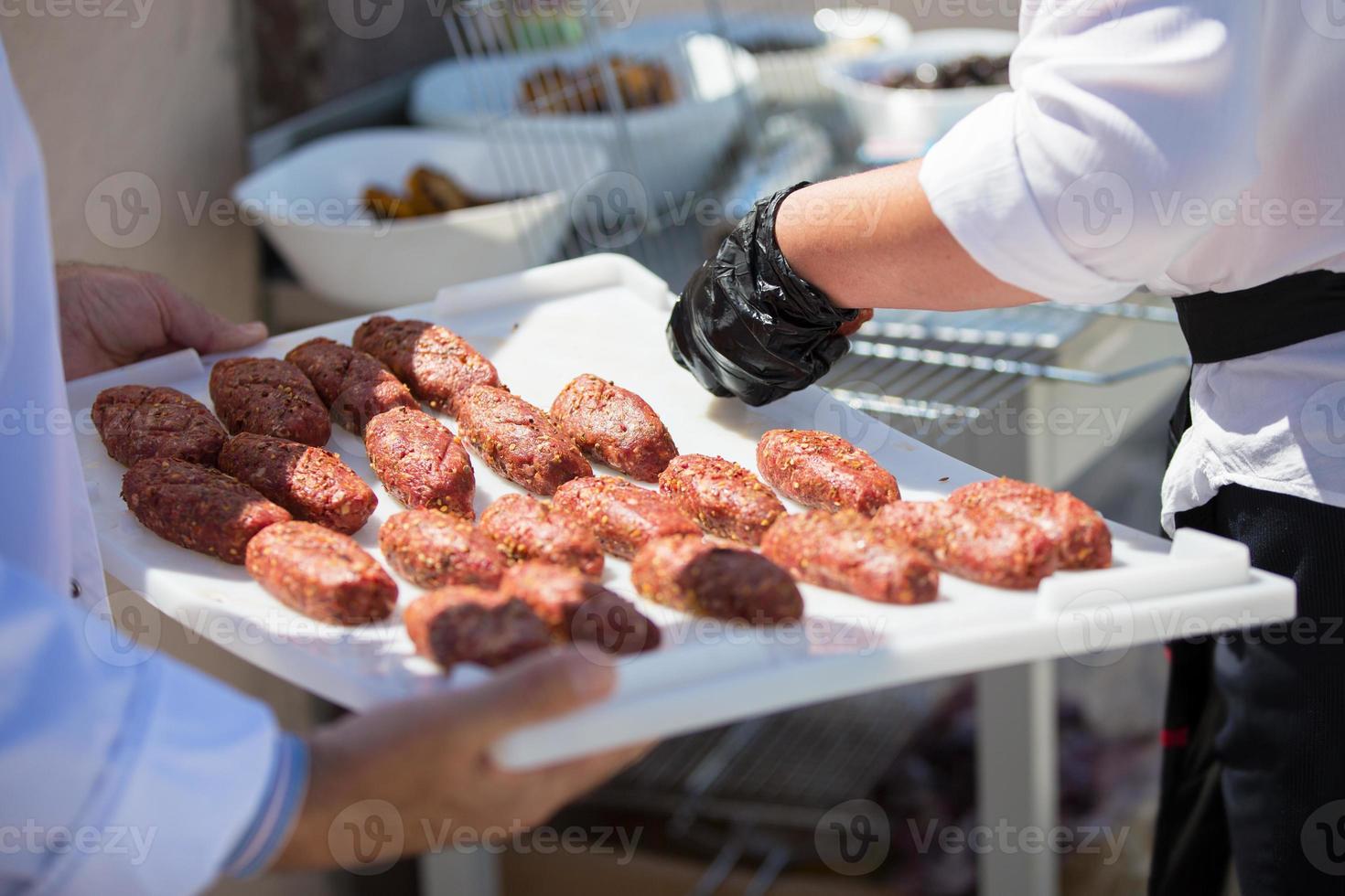 The chef's hands are holding a tray with semi-finished cutlets. photo