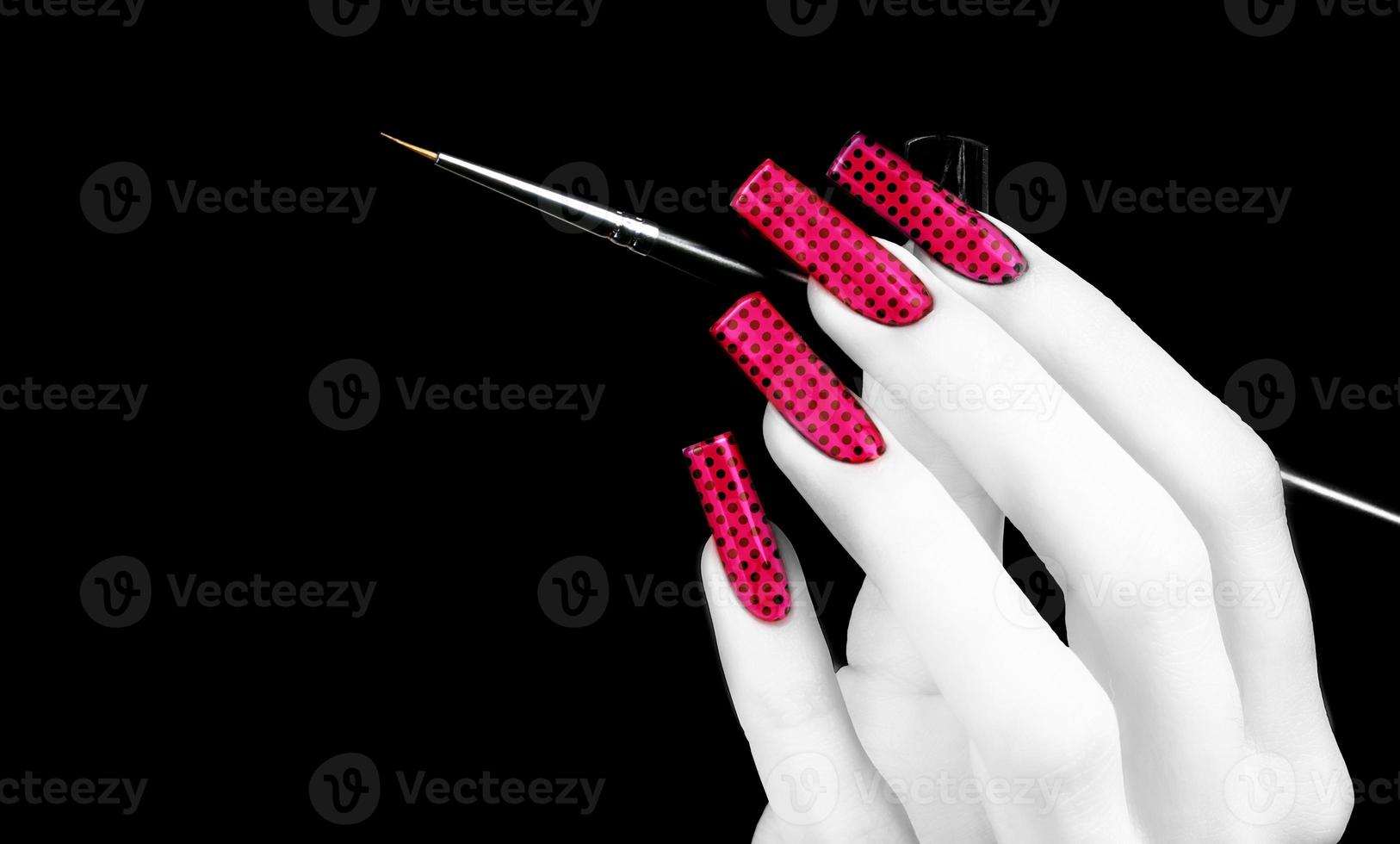 White hand with a beautiful manicure and brush on a black background. Nail design. Extended nails. photo