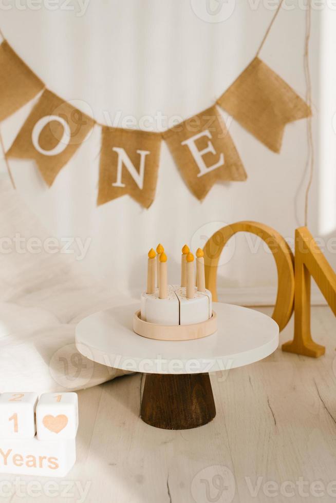 Photo zone for an anniversary or birthday with a mattress, wooden toys and a birthday cake.