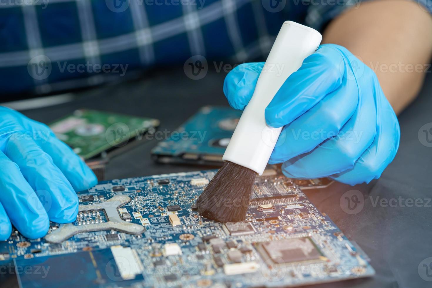 Asian technician repair and cleaning dirty micro circuit main board of smartphone electronic technology with brush, hardware, mobile phone, upgrade concept. photo