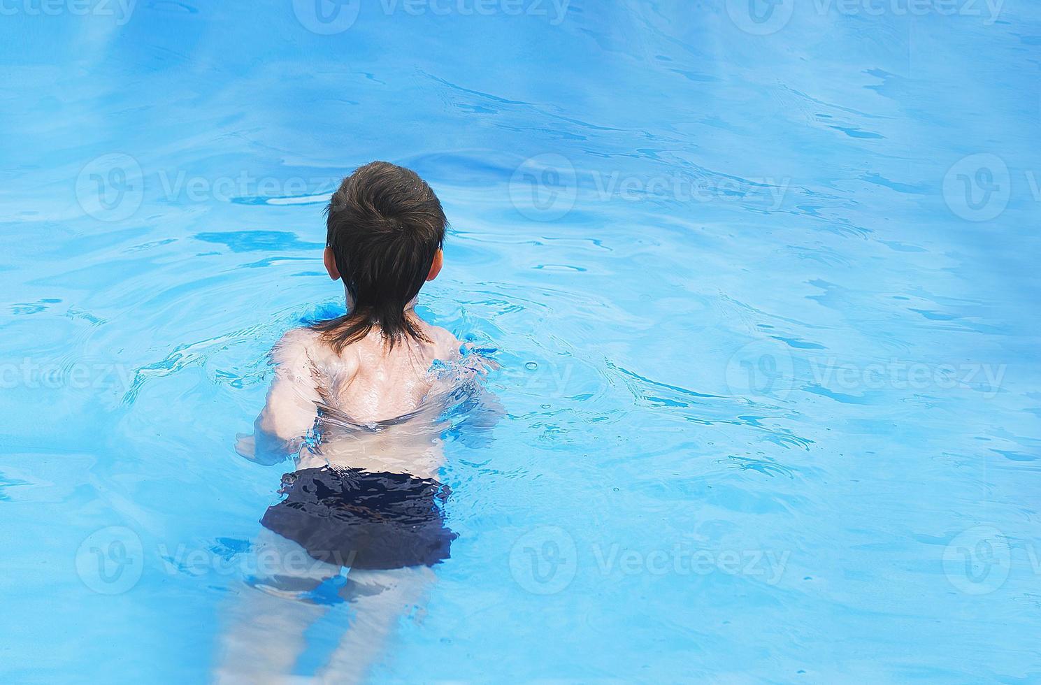 boy swims in the pool. boy learning to swim photo