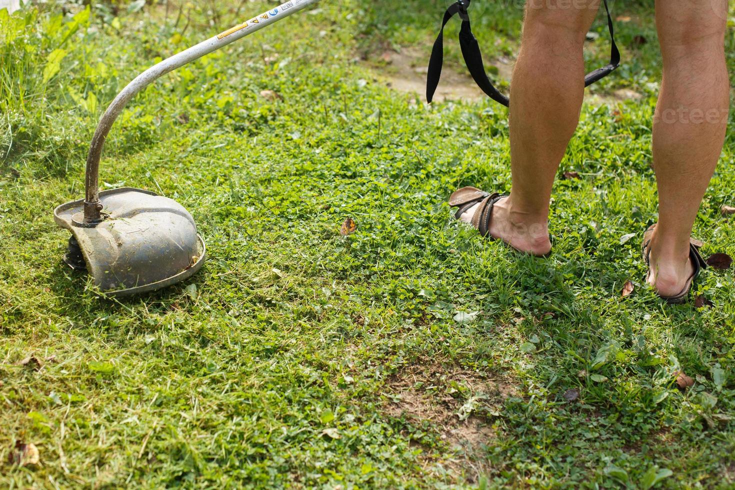 a man mows grass with a trimmer outdoor photo