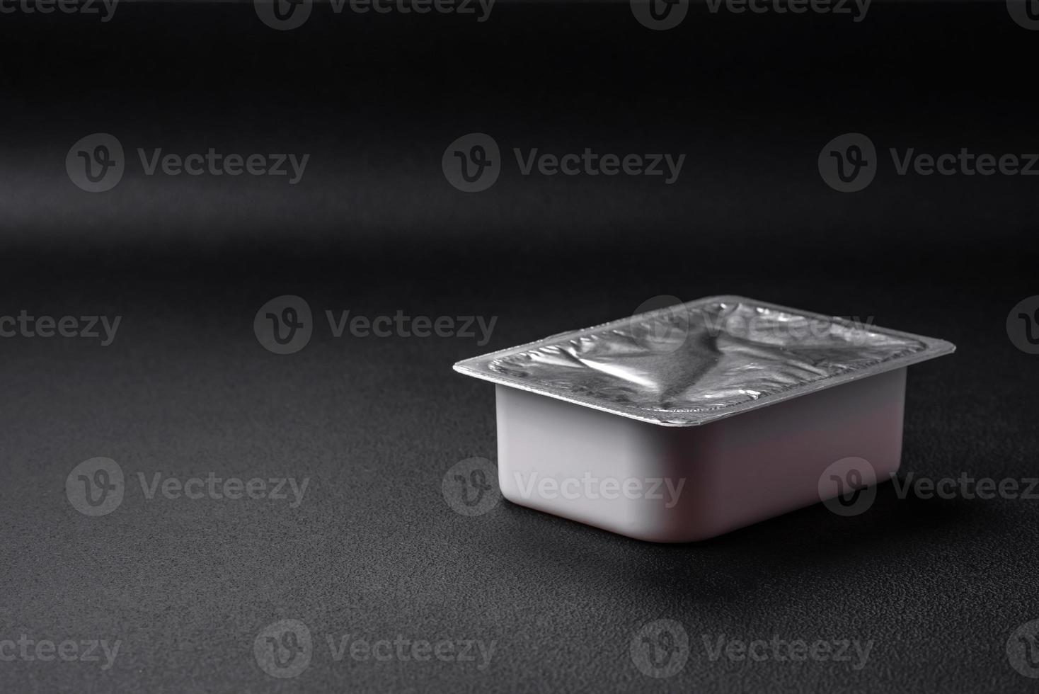 Rectangular plastic box with yogurt or cheese hermetically sealed with a foil lid photo