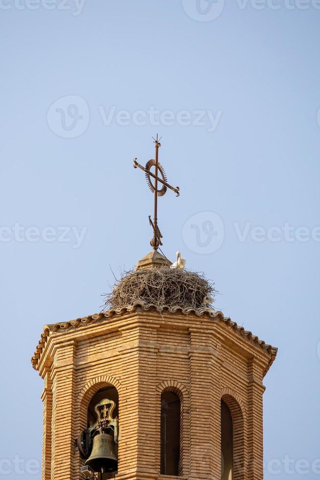 stork nest on the church tower against a blue sky with birds photo