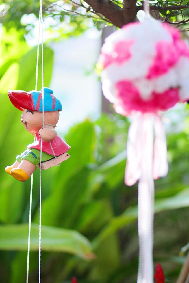 Artificial Pink flowers Hanging and Clay doll decoration on tree in marriage. Wedding decorative in the green garden outdoor. photo