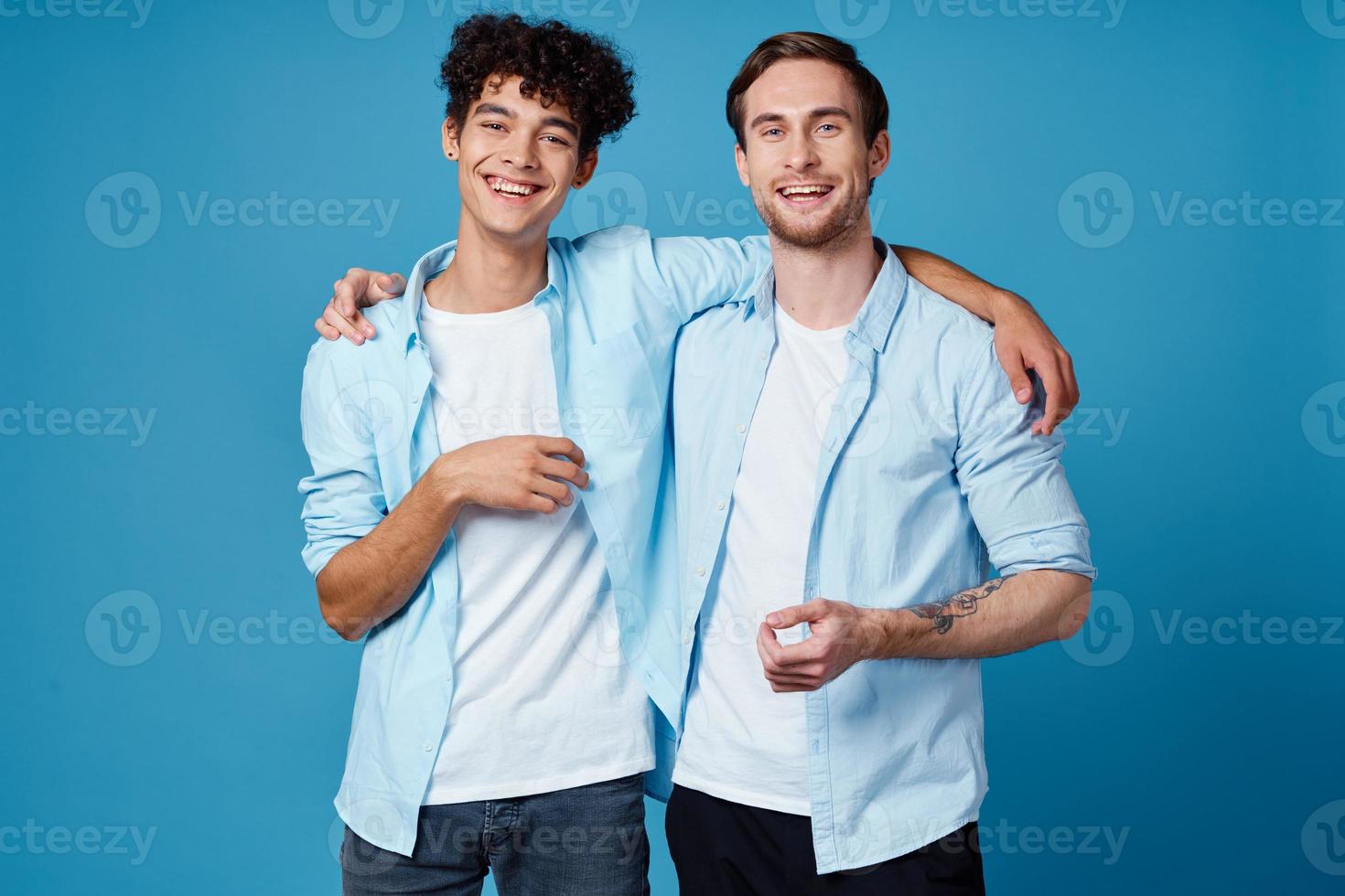 man with curly hair hugs his friend on blue background fun cropped view photo