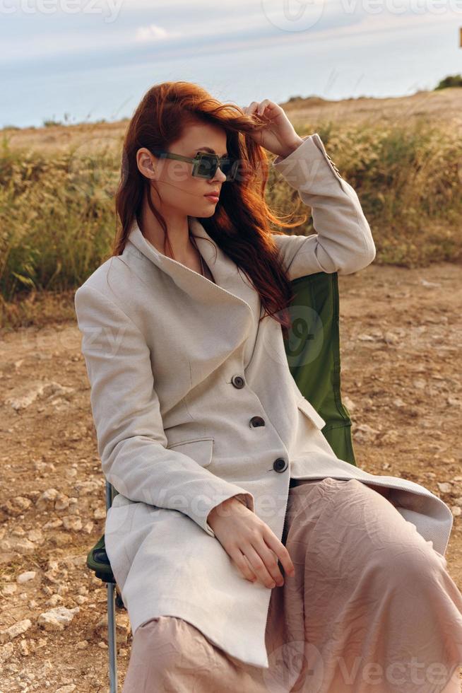 beautiful woman in a coat outdoors sitting on a chair harvest photo