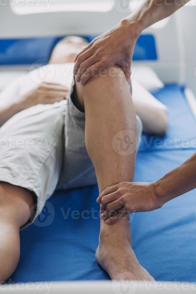 médico o fisioterapeuta trabajando examinando tratando lesionado brazo de atleta masculino paciente, extensión y ejercicio, haciendo el rehabilitación terapia dolor en clínica. foto