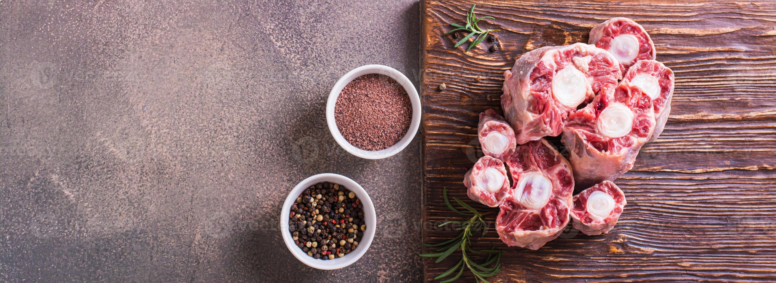 Pieces of raw oxtail and spices for cooking on a wooden board on the table top view web banner photo