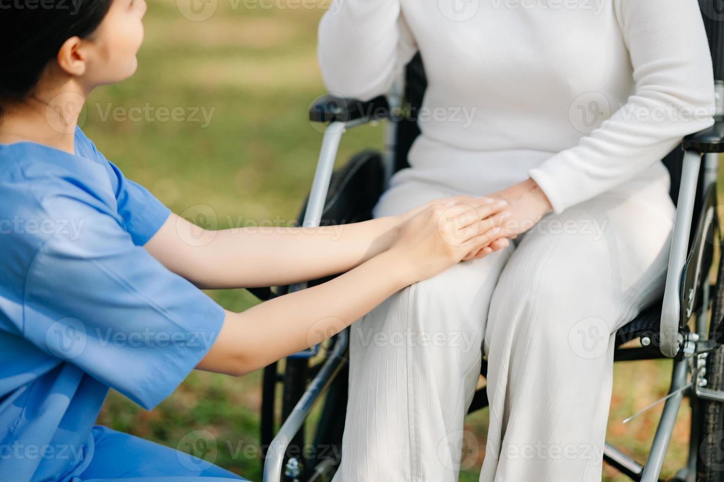 Elderly asian senior woman on wheelchair with Asian careful caregiver. Nursing home hospital garden concept. in sun light photo