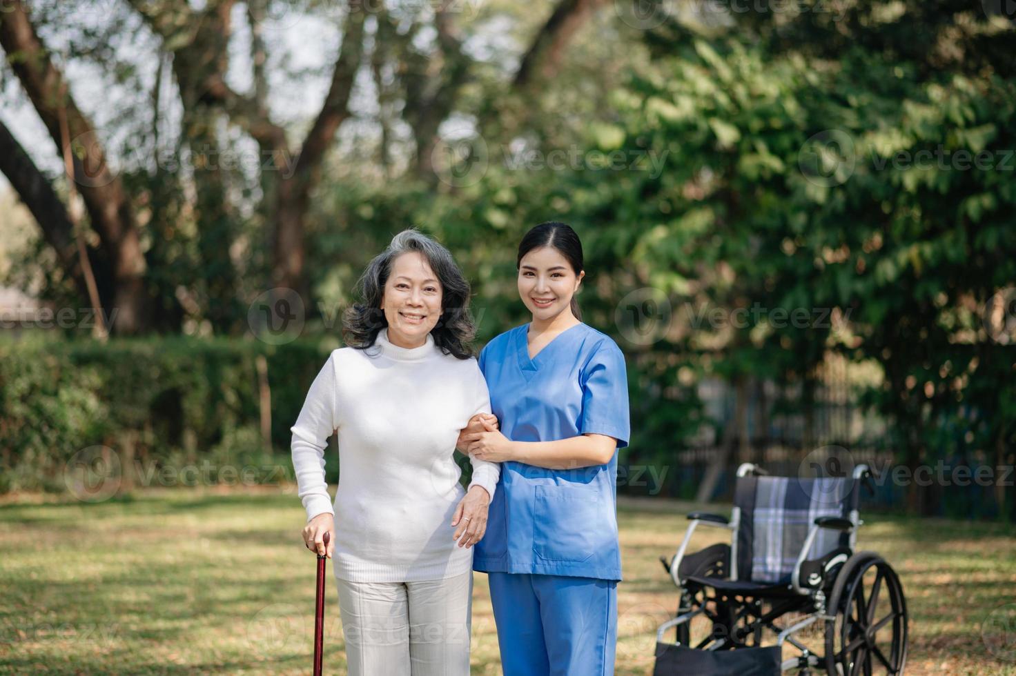 Elderly asian senior woman on wheelchair with Asian careful caregiver. Nursing home hospital garden concept. photo