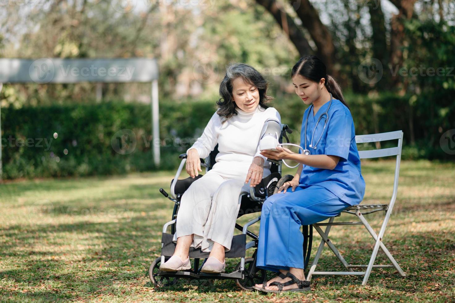 Senior woman being examined by a doctor in background. hospital garden concept. photo