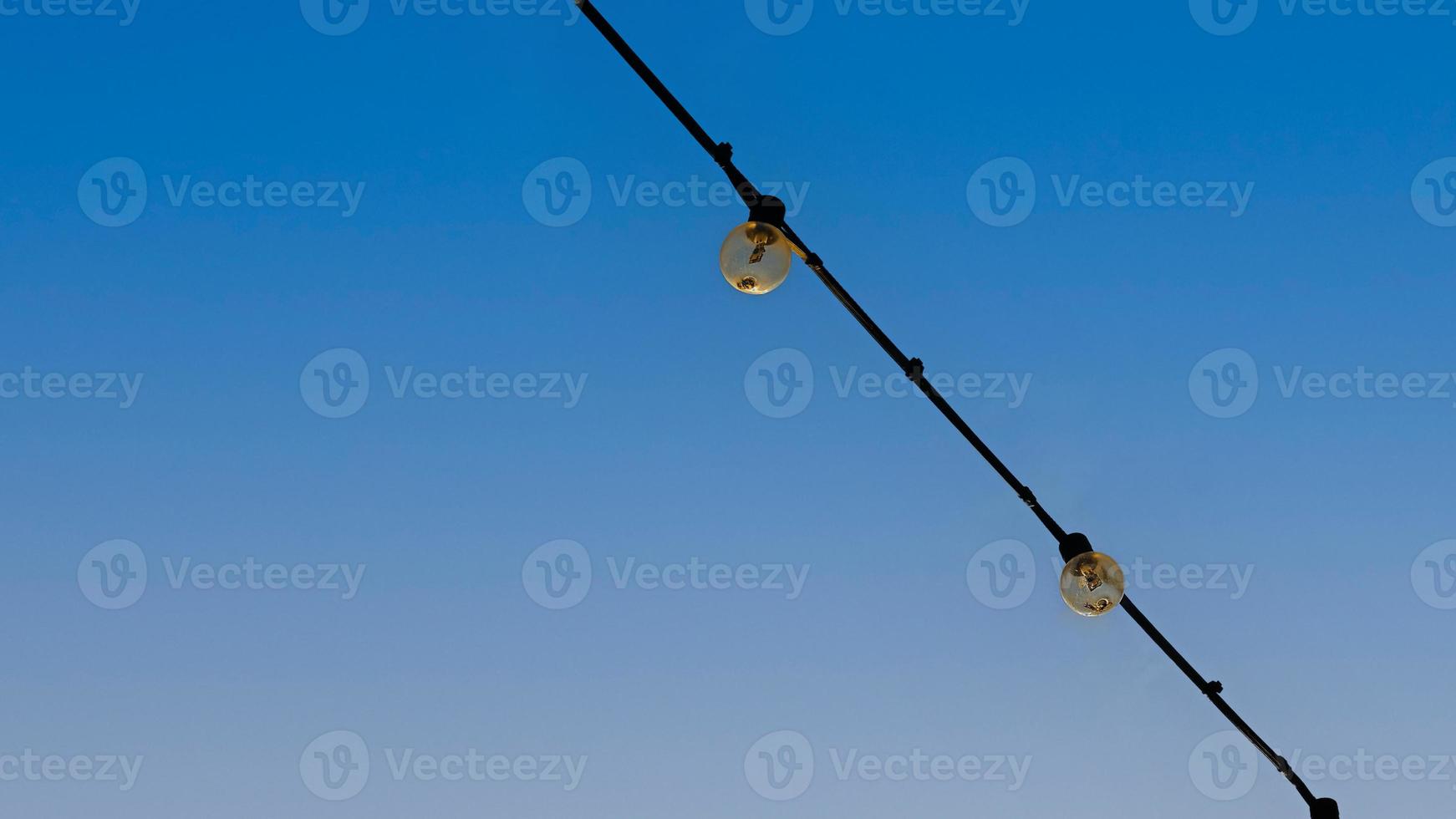 Group of Light bulbs hanging on wires against on blue sky. photo
