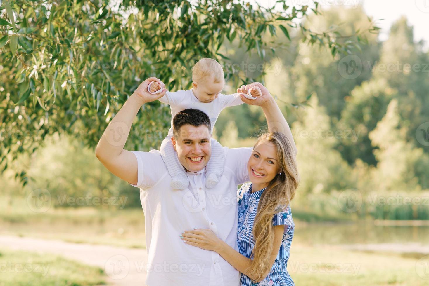 un contento joven familia con un linda pequeño hijo en el verano en el parque foto