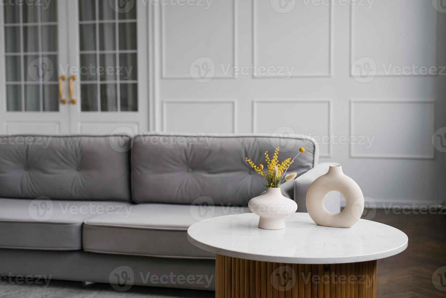 moderno elegante floreros en el café mesa cerca el gris sofá en el vivo habitación de el casa foto
