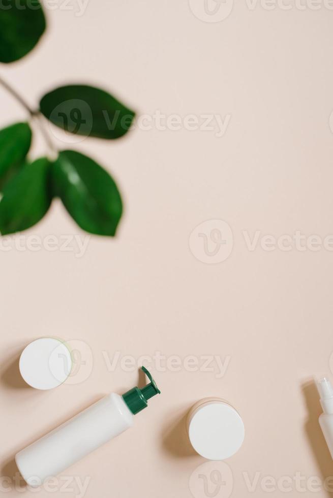 White cosmetic jar and a bottle of cream with a top view of the leaves of plants, a mock-up of the product design. Natural organic cosmetics photo