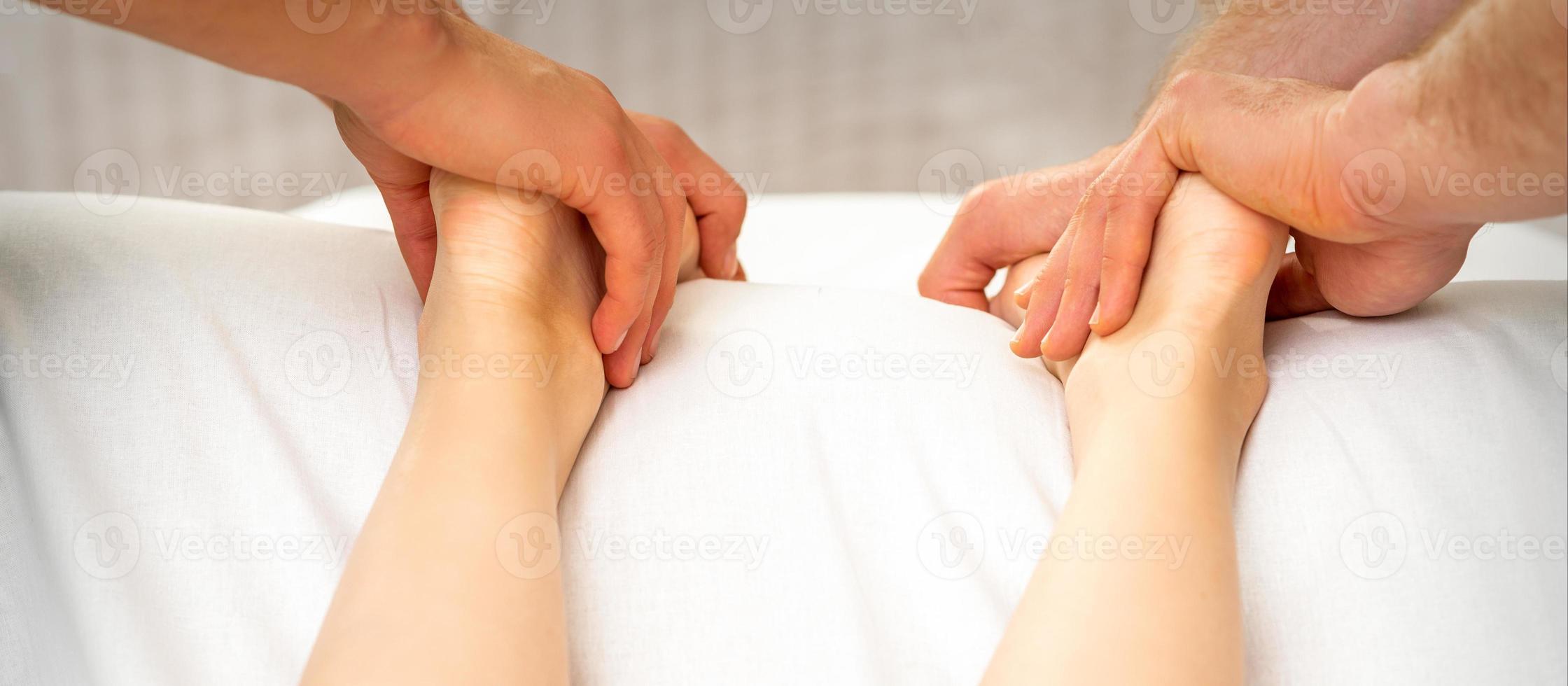 Two masseurs massaging feet of woman photo