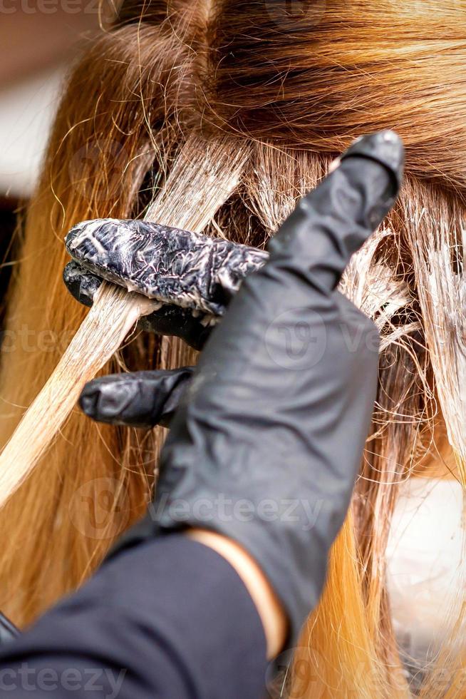 Hairdresser applying dye to strand of hair photo