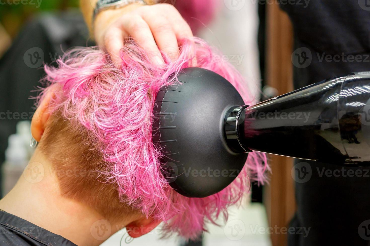 Hairdresser drying pink hair of client photo