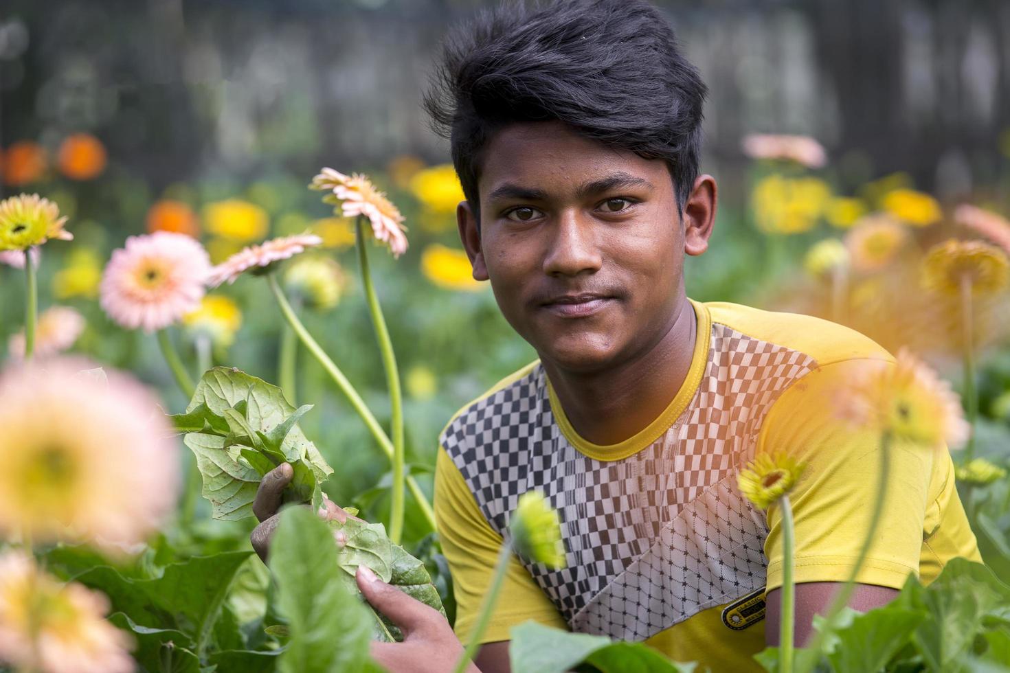 Bangladesh diciembre 07, 2017 un gerbera flor granjero mira a el cámara mientras tendiendo a el flores en su jardín a sabar, dhaka. foto