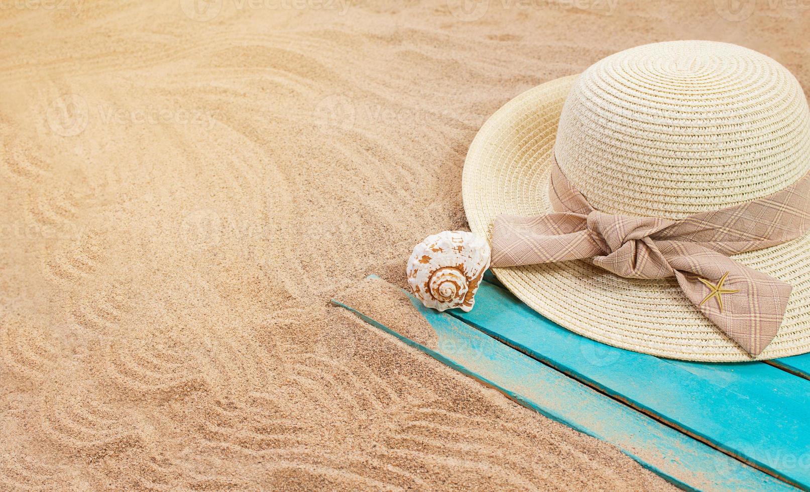 Sun hat with seashell and starfish on blue wooden board on sandy beach. Summer, vacation, tourism in hot country photo