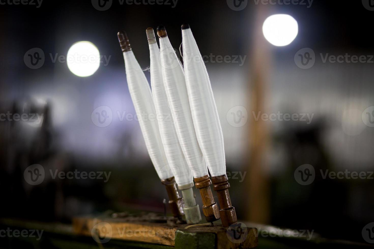 White yarn spools close-up in a yarn factory. White yarn spools in dark background. photo