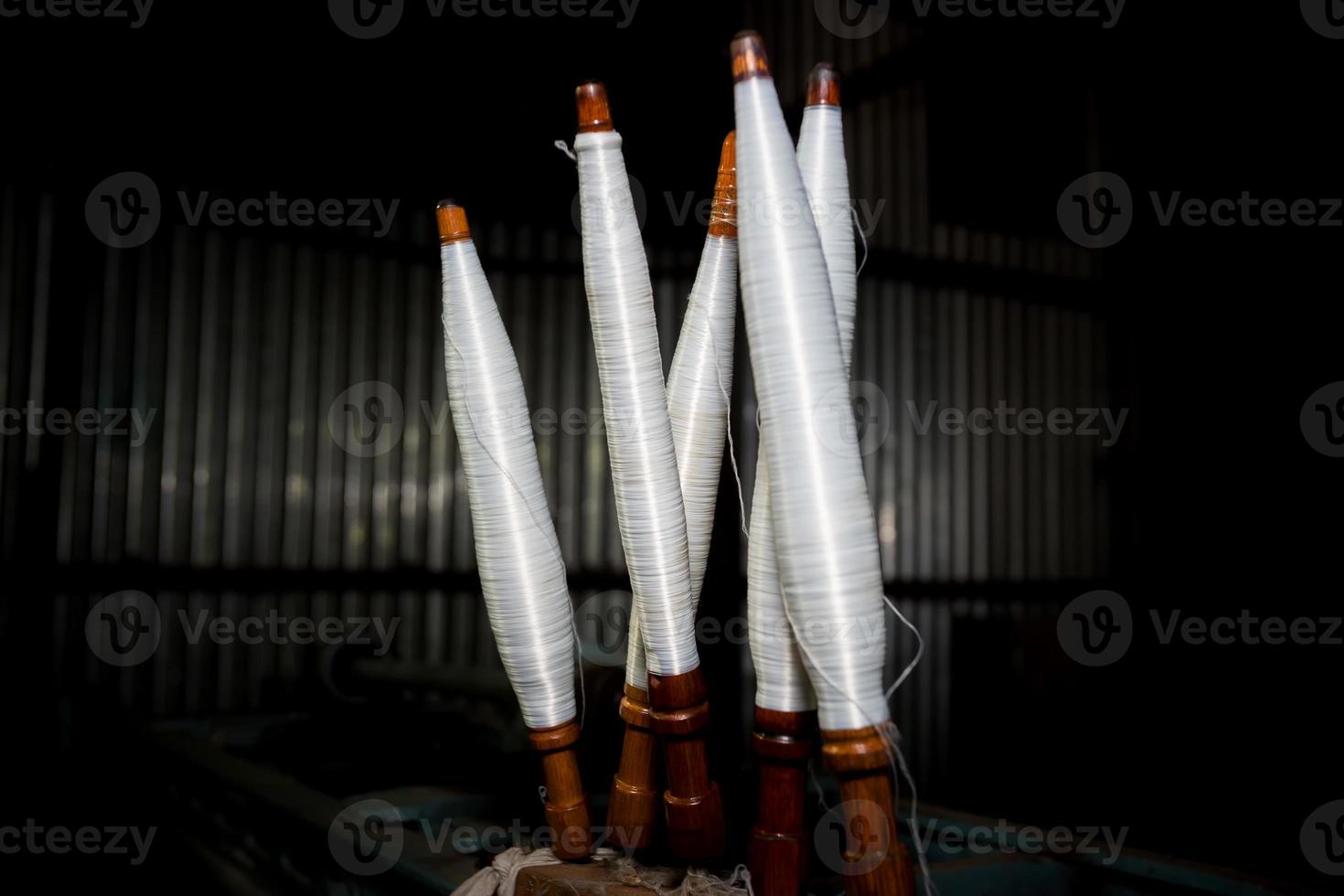 White yarn spools close-up in a yarn factory. White yarn spools in dark background. photo