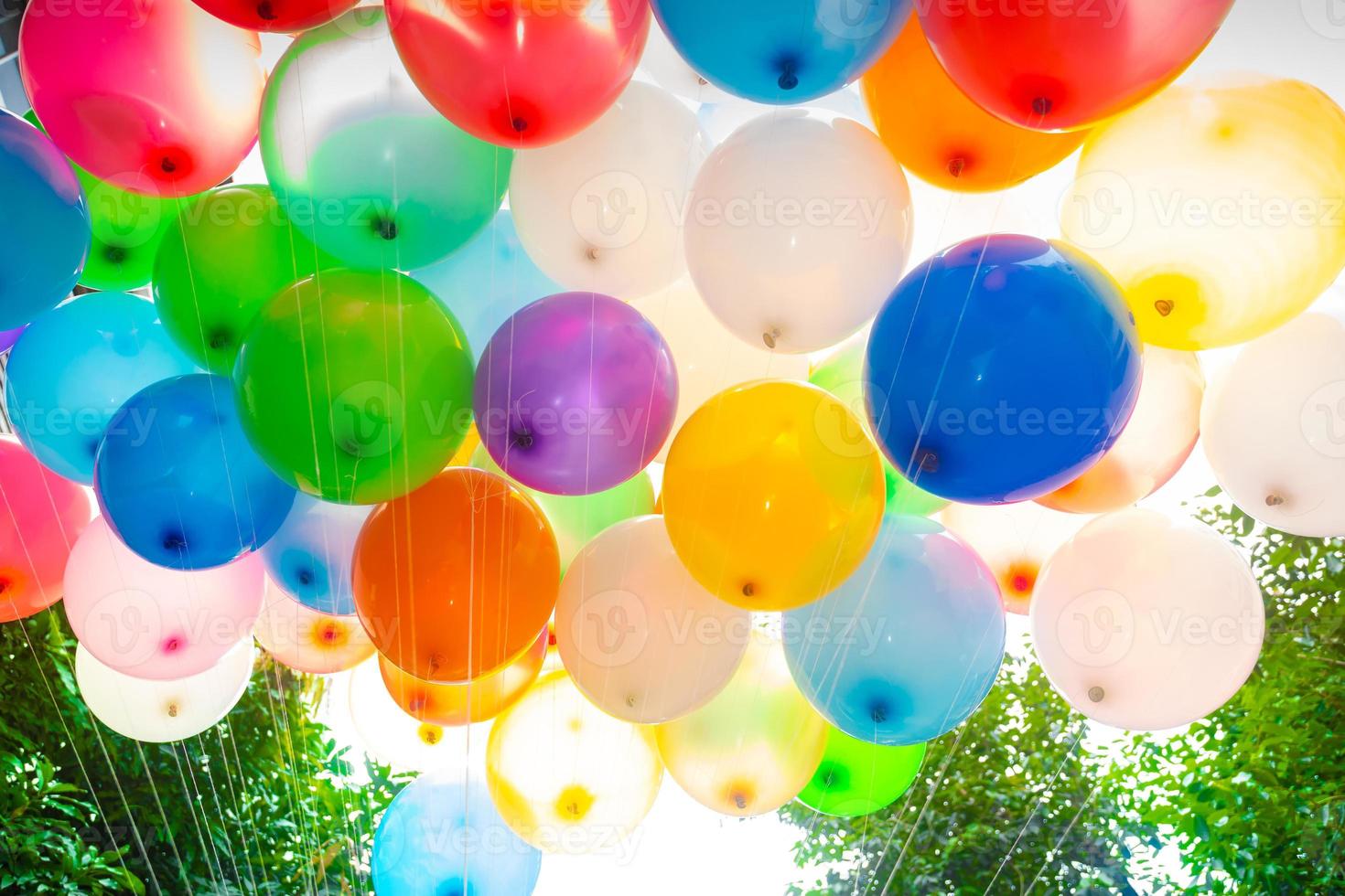 Sunlight against colorful gas-filled balloons attached to the yarn. Colorful balloons background. photo