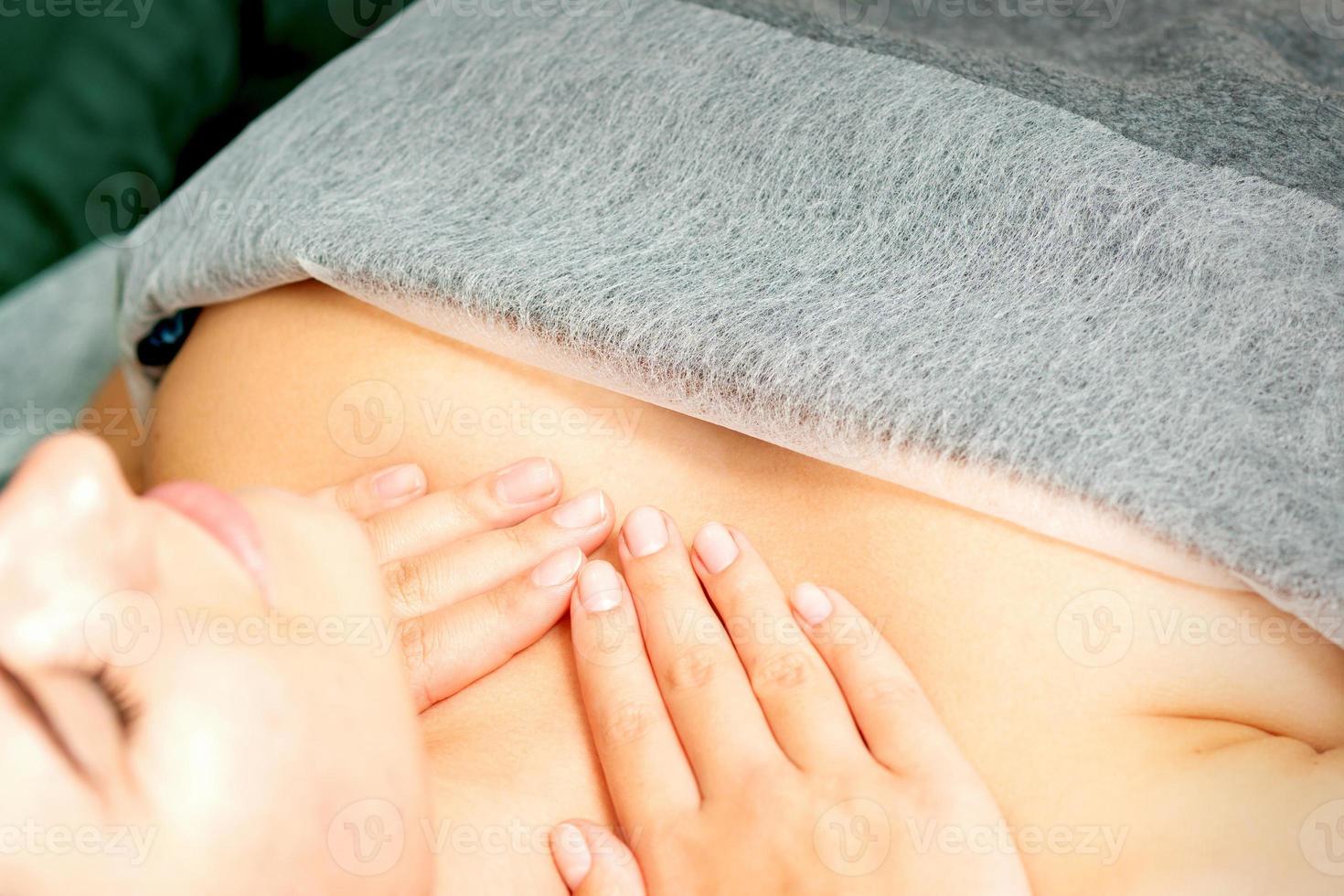 Masseuse makes a chest massage of a young caucasian woman in a spa salon. photo