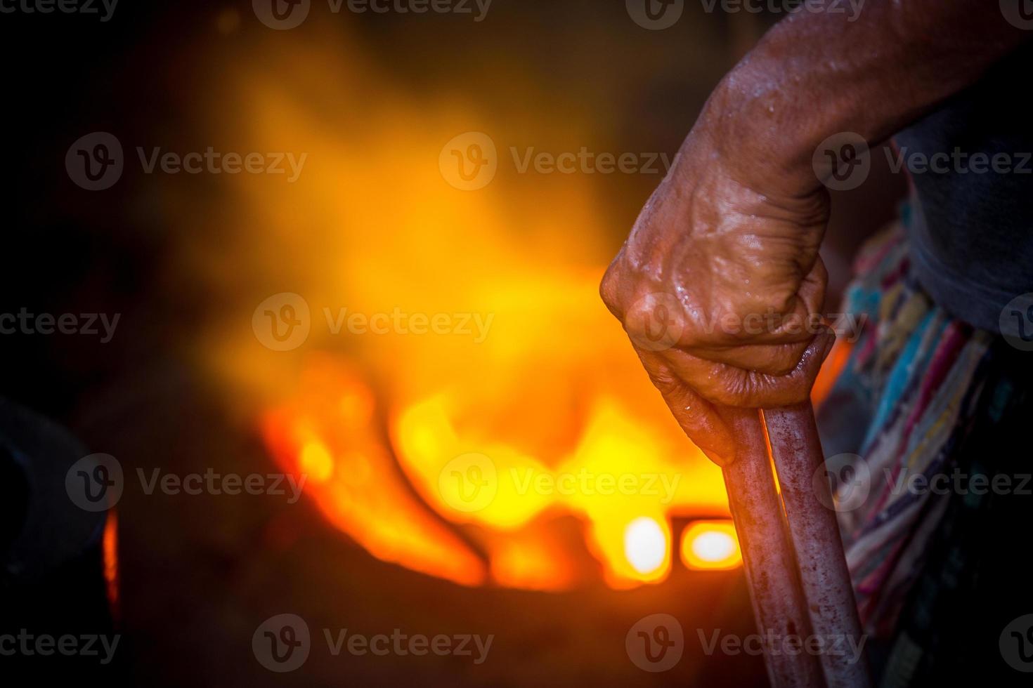 Unsafe worker hands. A local steel machine parts making yard worker melting scrap on hot furnace. photo
